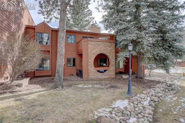 rear view of property featuring brick siding, crawl space, and a chimney