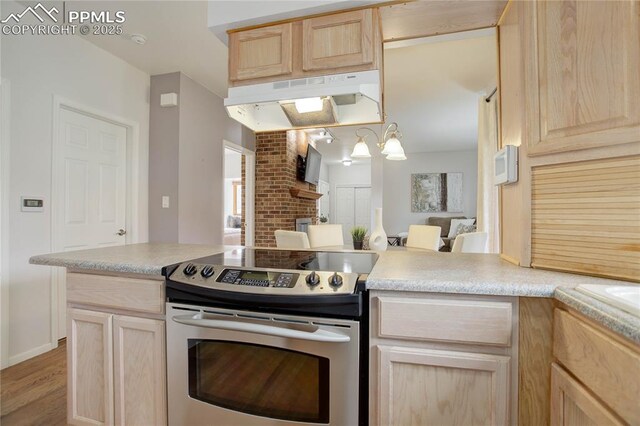 kitchen featuring light countertops, stainless steel range with electric stovetop, under cabinet range hood, a peninsula, and light brown cabinets