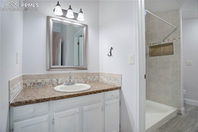 full bath with wood finished floors, a stall shower, and vanity