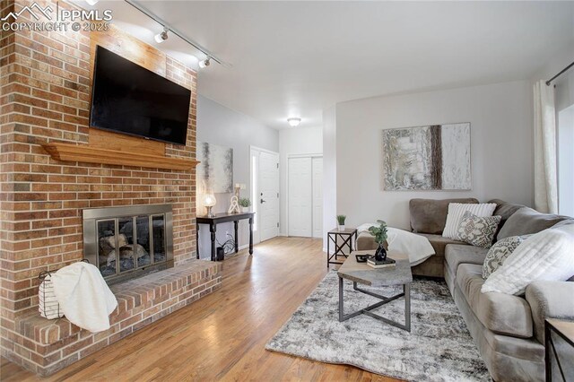 living room with rail lighting, a fireplace, and wood finished floors