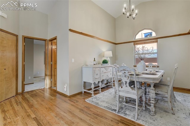 dining room featuring baseboards, high vaulted ceiling, wood finished floors, and an inviting chandelier