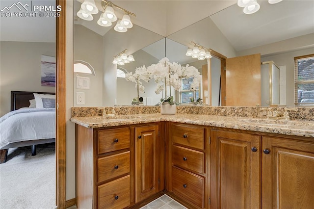 ensuite bathroom featuring connected bathroom, double vanity, vaulted ceiling, and a sink