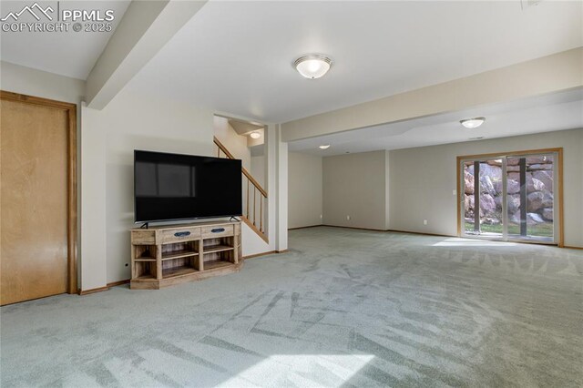 unfurnished living room featuring carpet, baseboards, and stairs