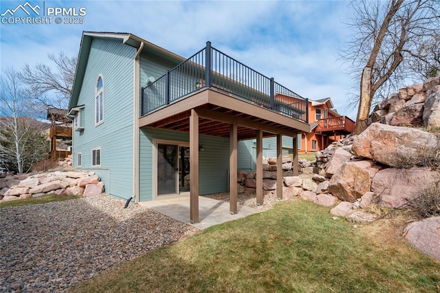 rear view of property featuring a wooden deck, a yard, and a patio area