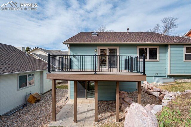 rear view of house with a shingled roof and a patio