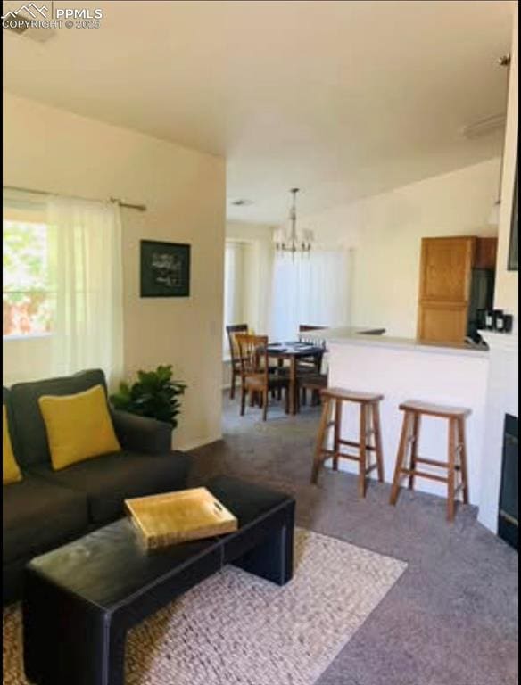 carpeted living area featuring a chandelier and lofted ceiling