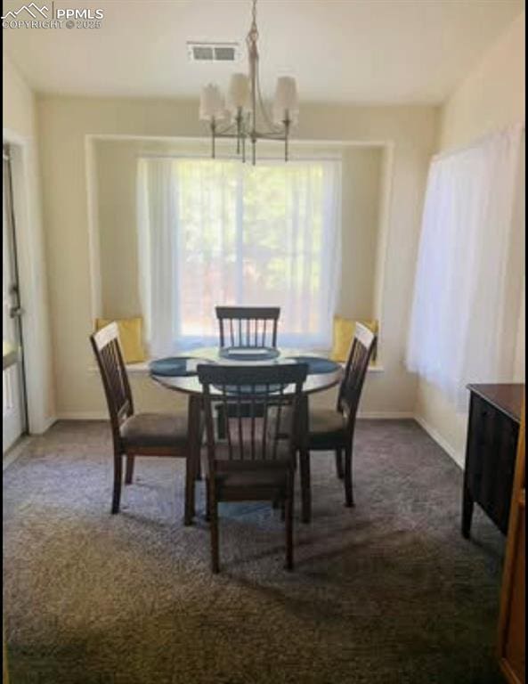 dining space with a chandelier, visible vents, baseboards, and dark colored carpet