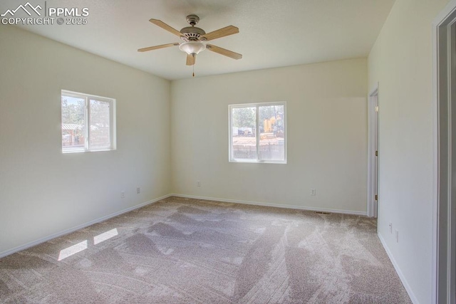 carpeted spare room featuring baseboards and ceiling fan