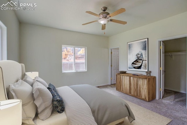 bedroom featuring a ceiling fan, baseboards, a spacious closet, a closet, and light colored carpet