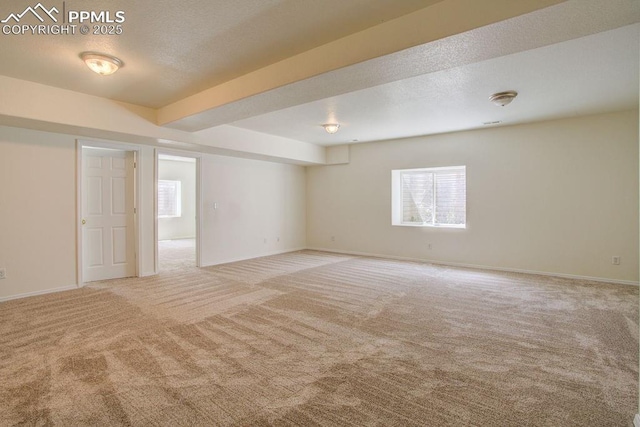 spare room featuring carpet flooring, baseboards, and a textured ceiling