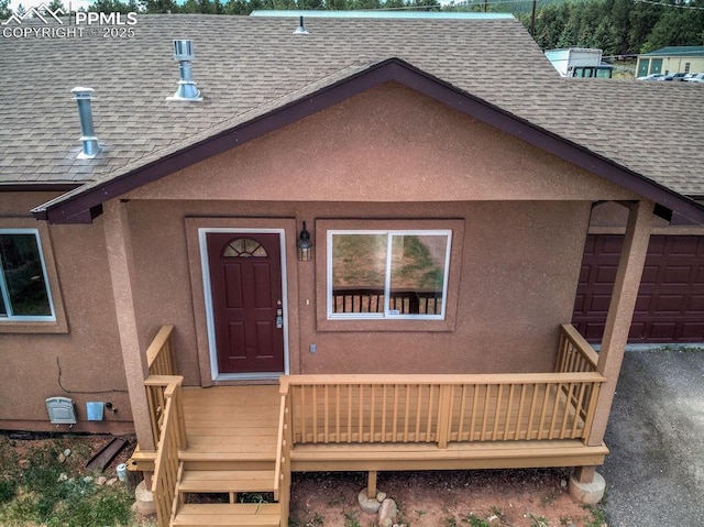 exterior space with a garage, roof with shingles, and stucco siding