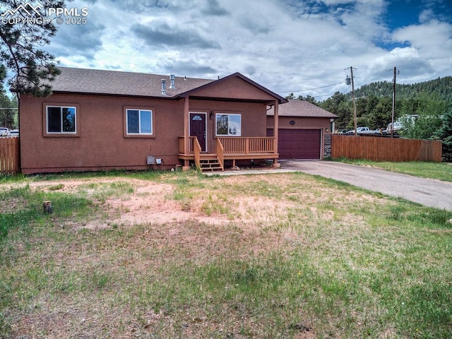 single story home featuring stucco siding, an attached garage, driveway, and fence