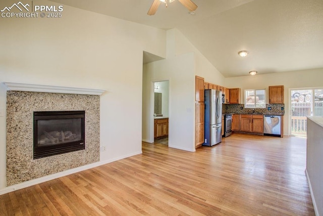 kitchen with open floor plan, a premium fireplace, brown cabinets, light wood-style flooring, and stainless steel appliances