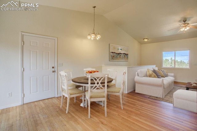 dining area featuring light wood-style flooring, ceiling fan with notable chandelier, baseboards, and high vaulted ceiling