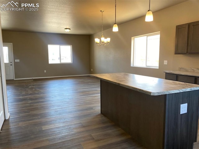 kitchen featuring a kitchen island, dark wood finished floors, light countertops, decorative light fixtures, and a notable chandelier