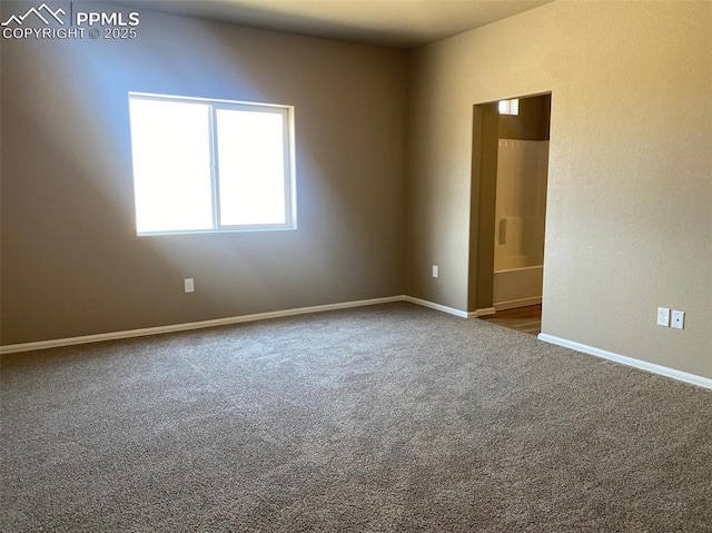 spare room with dark colored carpet and baseboards