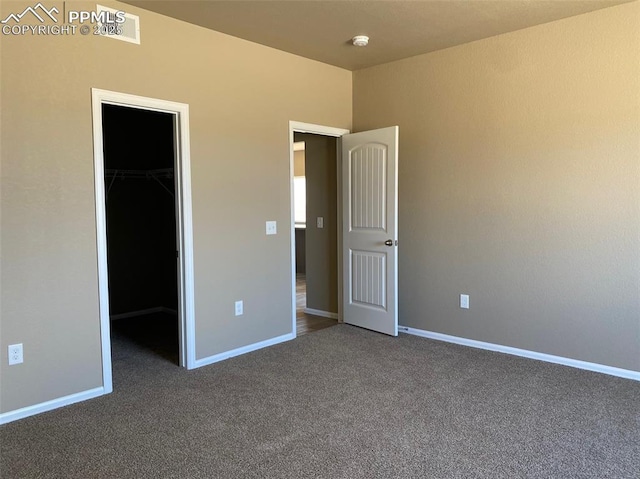 unfurnished bedroom featuring a spacious closet, carpet flooring, a closet, and baseboards