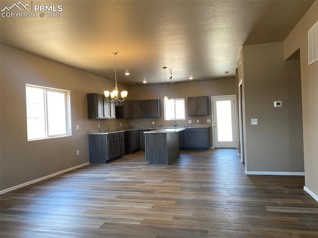 kitchen with a notable chandelier, a kitchen island, baseboards, and wood finished floors