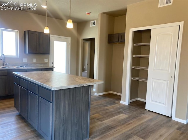 kitchen featuring a sink, visible vents, and dark wood-type flooring