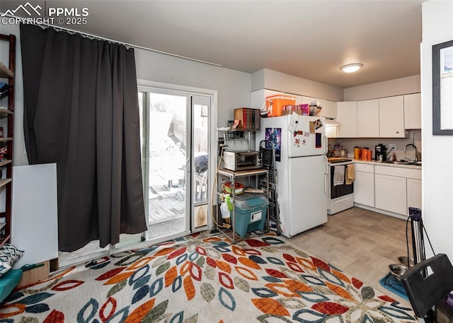 kitchen with light wood finished floors, under cabinet range hood, white appliances, white cabinetry, and a sink