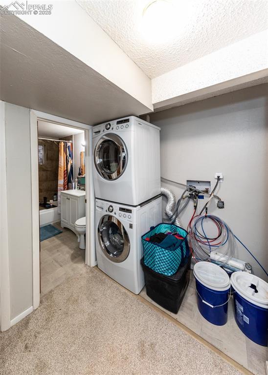 laundry area featuring laundry area, stacked washer and clothes dryer, and a textured ceiling