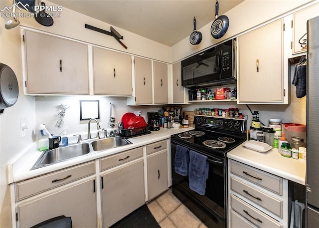 kitchen with light tile patterned floors, black appliances, light countertops, and a sink