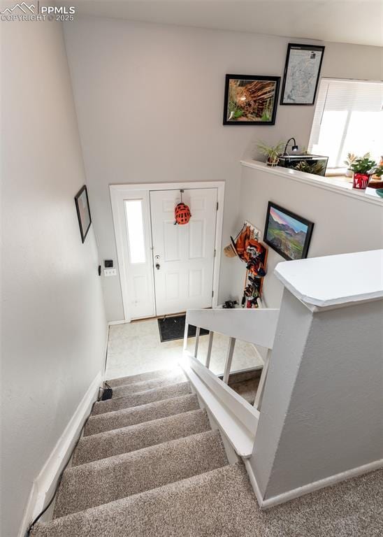 stairway featuring baseboards and carpet floors