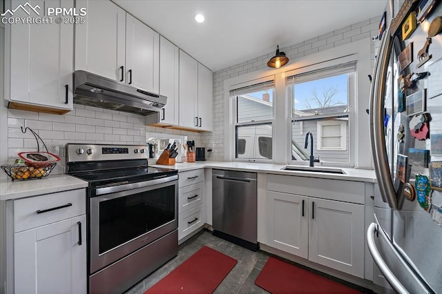 kitchen featuring under cabinet range hood, a sink, appliances with stainless steel finishes, light countertops, and decorative backsplash