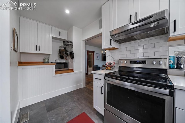 kitchen featuring visible vents, wainscoting, under cabinet range hood, appliances with stainless steel finishes, and white cabinetry