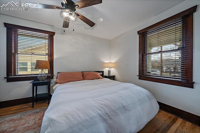 bedroom featuring a ceiling fan, baseboards, and wood finished floors