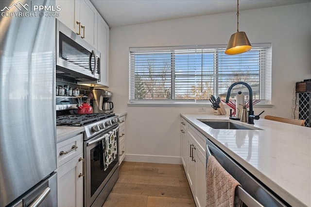 kitchen featuring light wood finished floors, white cabinets, stainless steel appliances, and a sink