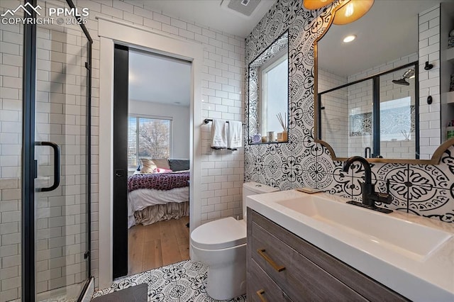 bathroom with visible vents, tile walls, vanity, a stall shower, and ensuite bath