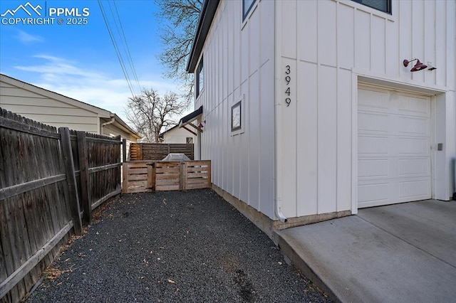 view of home's exterior featuring board and batten siding, a garage, and fence