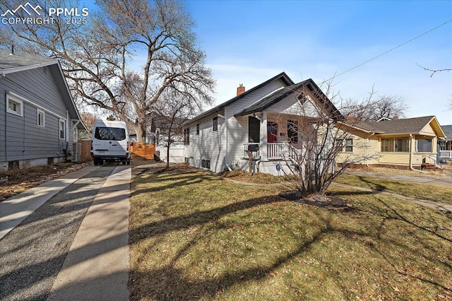 view of home's exterior with covered porch, a lawn, driveway, and a chimney