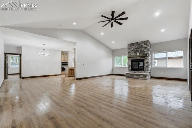 1309 Stone Ridge Dr, Woodland Park, CO 80863 - unfurnished living room with light wood-type flooring, baseboards, a stone fireplace, and ceiling fan with notable chandelier