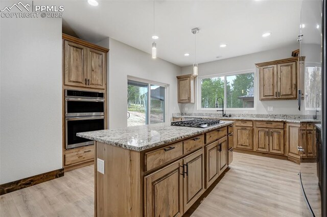 1309 Stone Ridge Dr, Woodland Park, CO 80863 - kitchen with a kitchen island, pendant lighting, light wood-type flooring, light stone counters, and appliances with stainless steel finishes