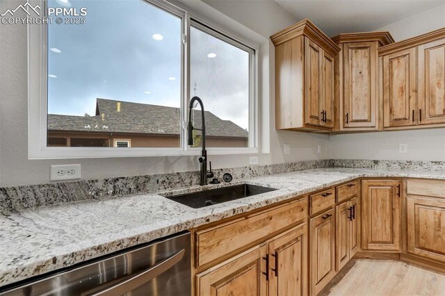 1309 Stone Ridge Dr, Woodland Park, CO 80863 - kitchen featuring light stone counters, dishwasher, light wood-style floors, and a sink