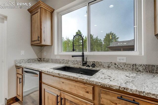 1309 Stone Ridge Dr, Woodland Park, CO 80863 - kitchen featuring light wood finished floors, light stone countertops, stainless steel dishwasher, brown cabinetry, and a sink