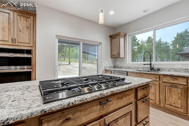 1309 Stone Ridge Dr, Woodland Park, CO 80863 - kitchen featuring light wood-type flooring, light stone counters, stainless steel double oven, gas stovetop, and a sink