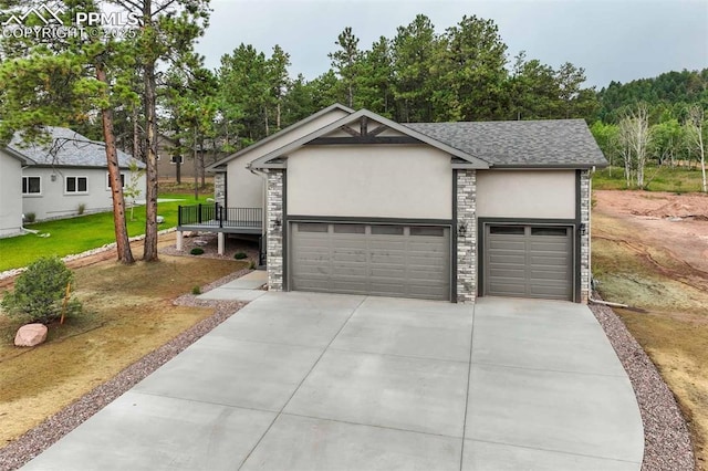 view of front of house featuring roof with shingles, driveway, stucco siding, a garage, and stone siding