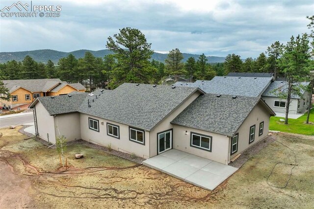 1309 Stone Ridge Dr, Woodland Park, CO 80863 - rear view of house featuring a patio area, a mountain view, stucco siding, and a shingled roof