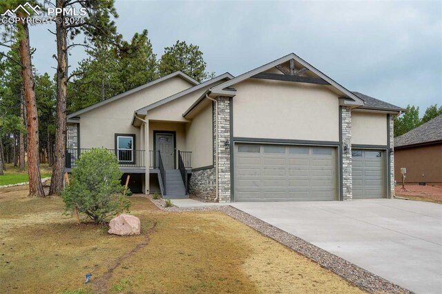 1309 Stone Ridge Dr, Woodland Park, CO 80863 - view of front facade featuring concrete driveway, a garage, stone siding, and stucco siding