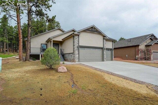 1309 Stone Ridge Dr, Woodland Park, CO 80863 - view of front of house with concrete driveway, an attached garage, stone siding, and stucco siding