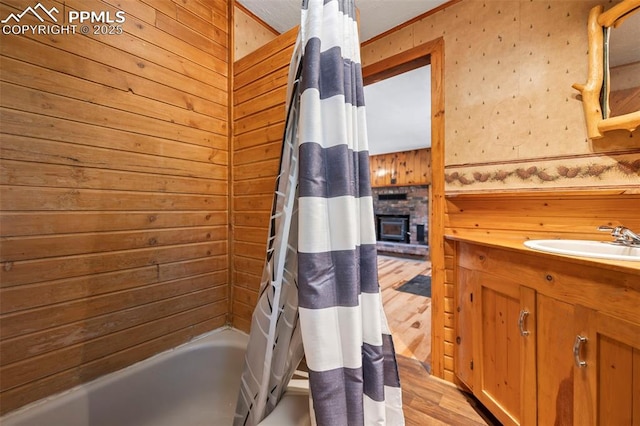 987 Blossom Rd, Woodland Park, CO 80863 - bathroom with a brick fireplace, vanity, shower / bath combo with shower curtain, and wood finished floors