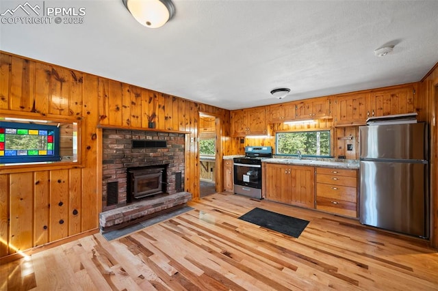 987 Blossom Rd, Woodland Park, CO 80863 - kitchen with wood walls, light wood-type flooring, light countertops, appliances with stainless steel finishes, and a sink
