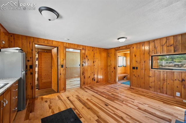 987 Blossom Rd, Woodland Park, CO 80863 - kitchen with light wood finished floors, wooden walls, brown cabinetry, and freestanding refrigerator