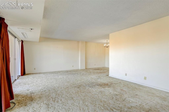 carpeted empty room with a notable chandelier and a textured ceiling