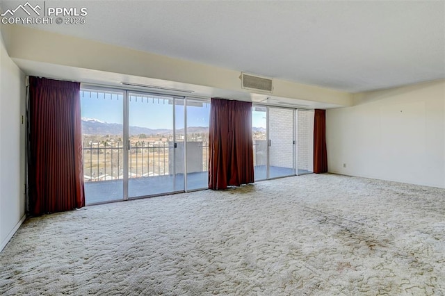 unfurnished room with visible vents, a mountain view, and carpet flooring