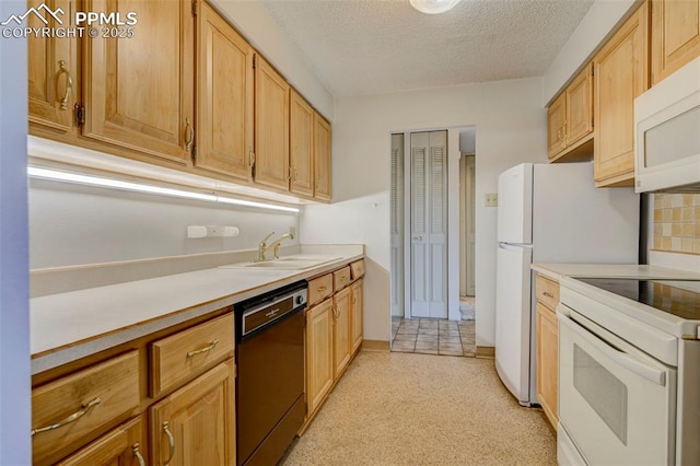 kitchen featuring a textured ceiling, white appliances, light countertops, and a sink