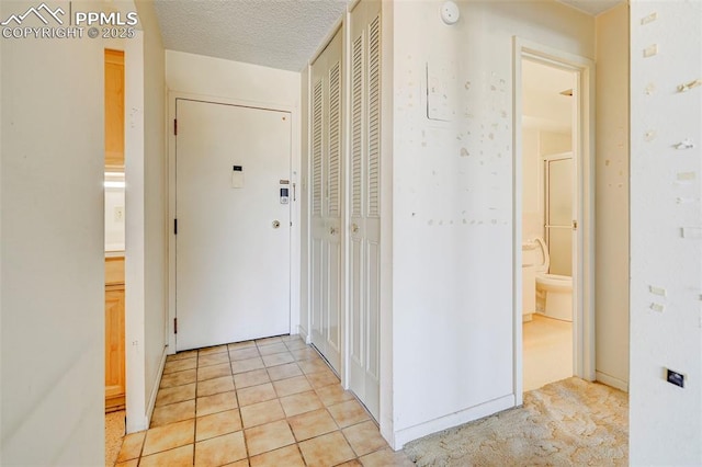 hall featuring light tile patterned flooring and a textured ceiling